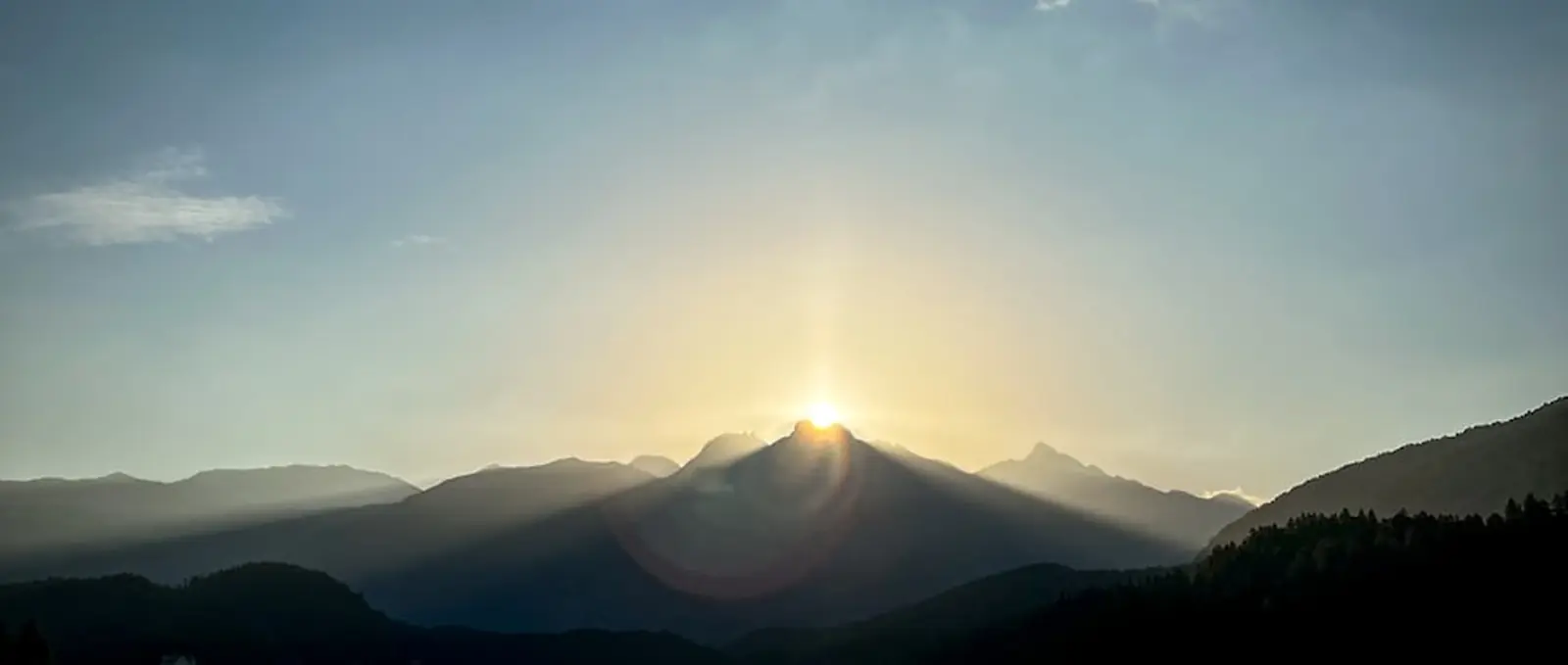 The sun low over an alpine lake.